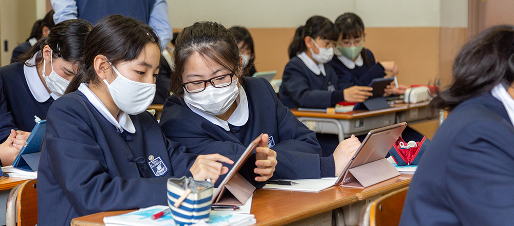 2人で1つのタブレットを共有する女子生徒