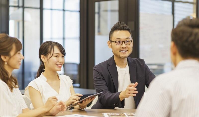 オフィスのワーキングスペースで社員同志がコミュニケーションをとっている